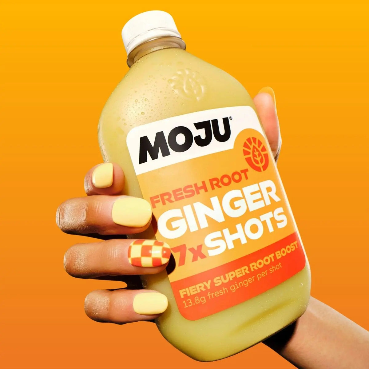 Hand with brightly painted fingernails holding on a dosing bottle of MOJU Ginger Shots